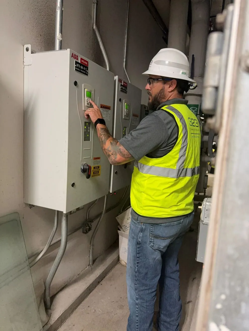 Brandt Elledge at a bank of ABB variable frequency drives, checking a drive keypad.
