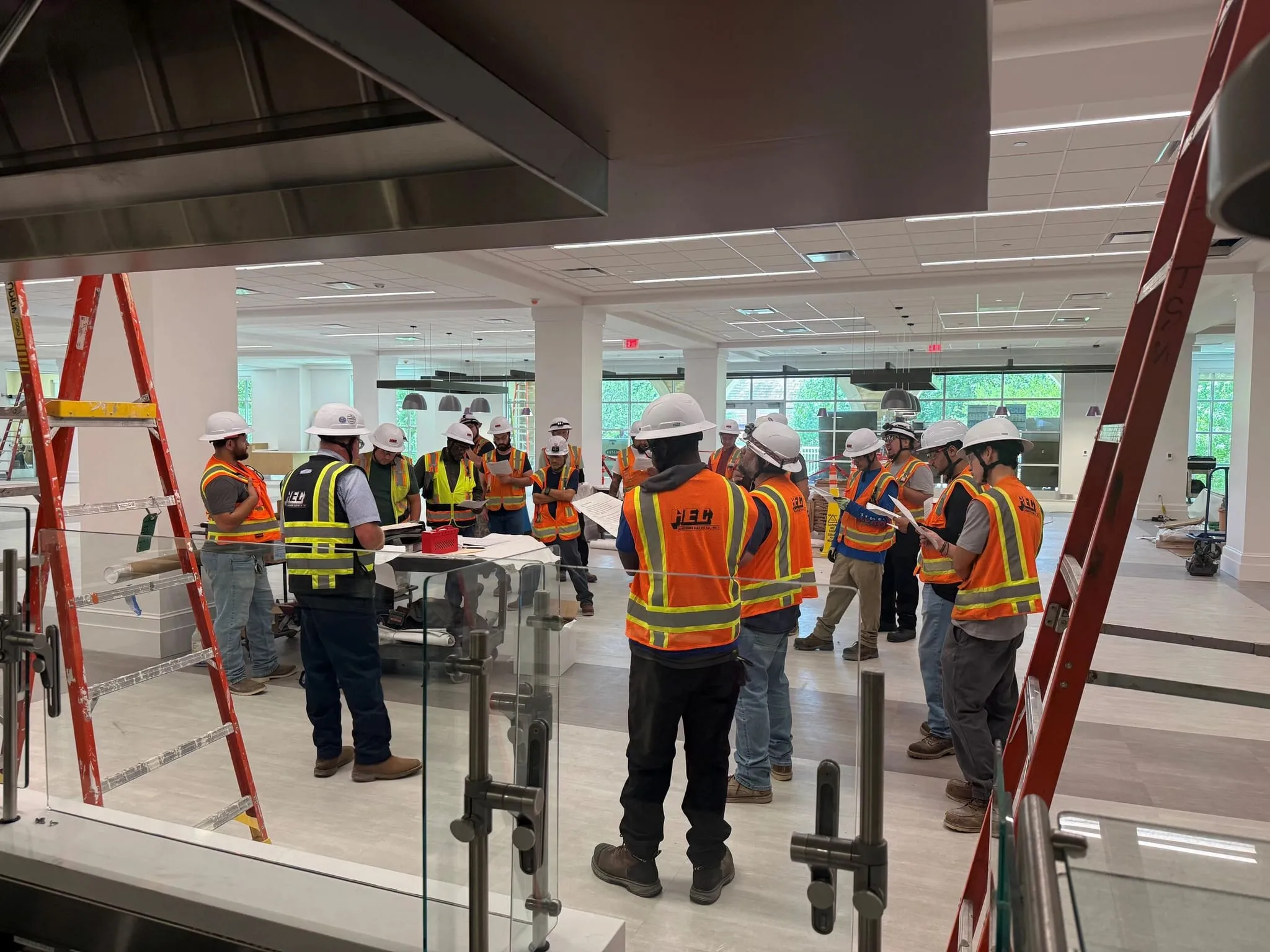 A coordination meeting on an active interior fit-out, trades gathered around drawings on a table.
